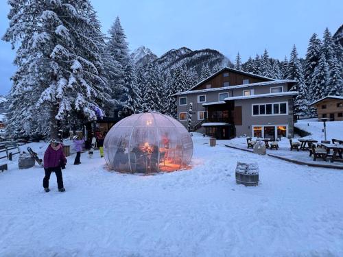 a person standing next to a fire in a dome in the snow at Chalet Queen in Canazei