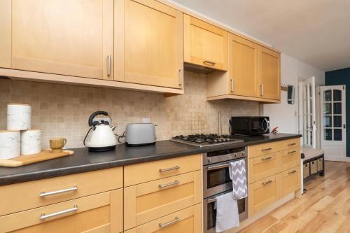 a kitchen with wooden cabinets and a stove top oven at WiFi | Parking | Near Major Attractions in Bath