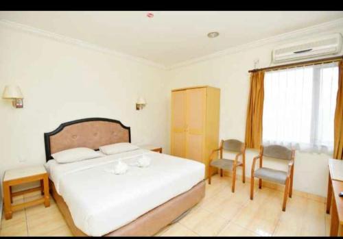 YUTA HOTEL في مانادو: غرفة نوم بسرير وطاولة وكراسي
