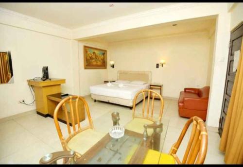 YUTA HOTEL في مانادو: غرفة معيشة مع سرير وطاولة وكراسي