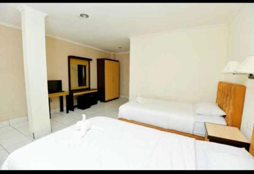 Habitación de hotel con 2 camas y TV en YUTA HOTEL, en Manado