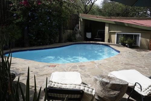 una gran piscina con 2 sillas y una mesa en ALLURING SELF CATERING 2 BEDROOM VILLA at BOKMAKIERIE VILLAS en Windhoek