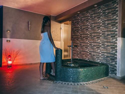a woman in a dress standing next to a brick wall at Monastero Resort & Spa - Garda Lake Collection in Soiano del Lago