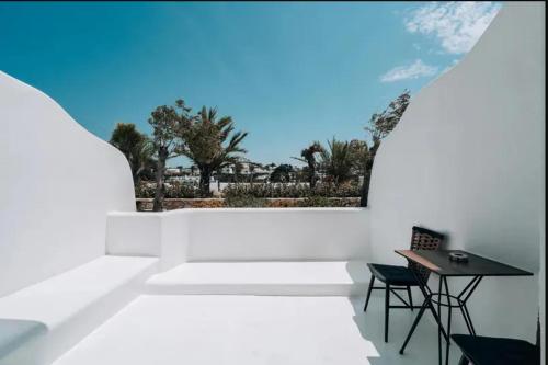 um quarto branco com uma mesa, uma mesa e cadeiras em Akkadian LGBT Only Boutique Hotel em Míconos