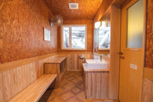 a wooden bathroom with a sink and a window at Kussharoko Sauna Club in Teshikaga