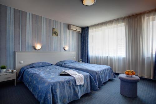 a hotel room with a bed with a blue blanket at Hotel Rahovets in Gorna Oryakhovitsa