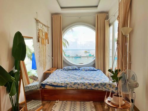 a bedroom with a bed and a large window at sunset beach house 3 in Phu Quoc