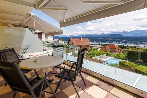 a balcony with a table and chairs and a view at Sun & See in Velden am Wörthersee