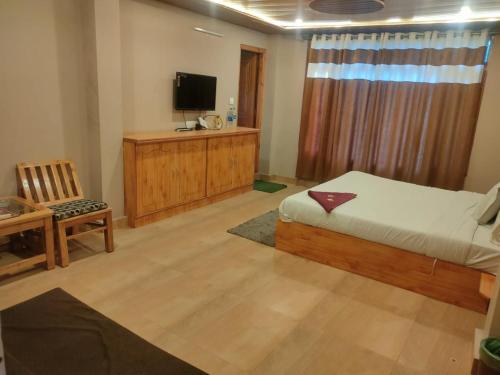 1 dormitorio con 1 cama, TV y silla en hotel inn en Manāli