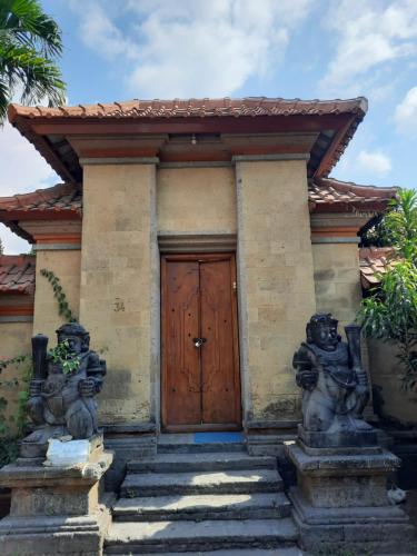 a house with a wooden door and two statues at Villia magnolia sanur bali 巴厘島玉蘭別墅 in Denpasar