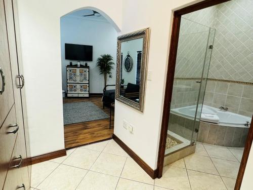 a bathroom with a shower and a tub and a mirror at Wisteria Place@3 Boschdal Rustenburg in Rustenburg