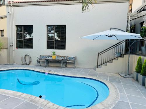 a swimming pool with a table and an umbrella at Wisteria Place@3 Boschdal Rustenburg in Rustenburg