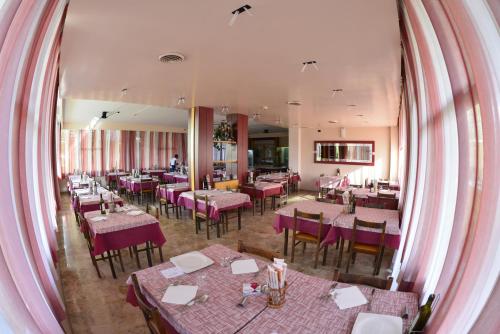 ein Restaurant mit Tischen und Stühlen und einem großen Spiegel in der Unterkunft HOTEL LA PLAYA in Cervia