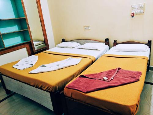 two beds in a room with towels on them at Hotel Varsha Hampi in Hampi