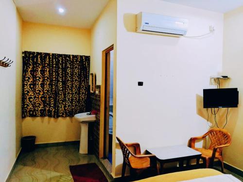 a room with a bed and a table and a sink at Hotel Varsha Hampi in Hampi