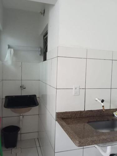 La salle de bains est pourvue de carrelage blanc, d'un lavabo et de toilettes. dans l'établissement Refúgio Termal: Seu Paraíso em Caldas novas, à Caldas Novas