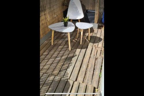 2 Stühle und ein Tisch auf einer Holzterrasse in der Unterkunft Charmant appartement - terrasse in LʼÎle-Saint-Denis