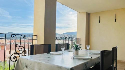 - une table avec des verres et des assiettes sur le balcon dans l'établissement Appartement Les Oliviers L'ILE ROUSSE, à LʼÎle-Rousse