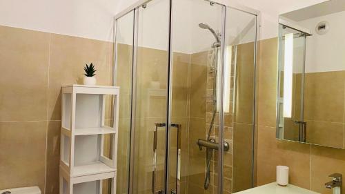 La salle de bains est pourvue d'une douche avec une porte en verre. dans l'établissement Appartement Les Oliviers L'ILE ROUSSE, à LʼÎle-Rousse