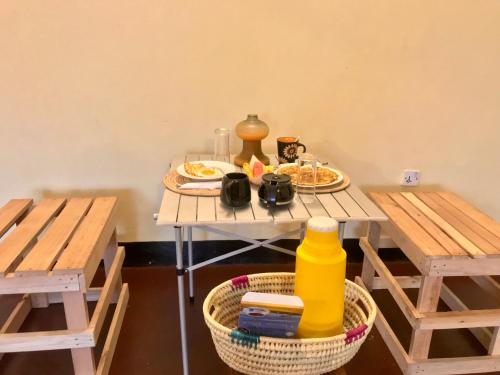 einem Tisch mit zwei Bänken und einem Tisch mit Essen darauf. in der Unterkunft Nomads nest safari house in Arusha