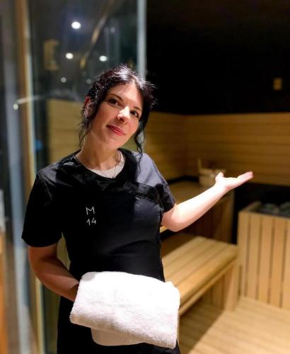 a woman standing in a sauna holding a towel at M14 Hotel & Spa in Padova