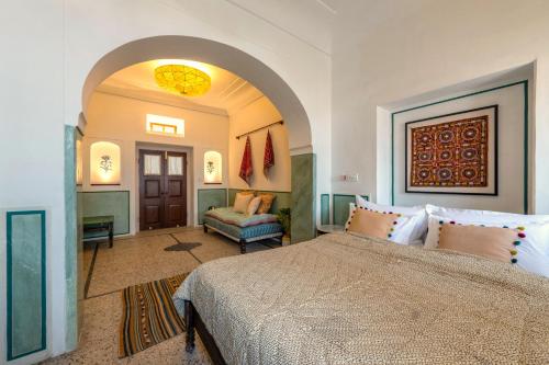 a bedroom with a large bed and a chair at Sum Jaipur in Jaipur