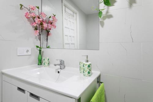 ein Badezimmer mit einem Waschbecken und einer Vase mit rosa Blumen in der Unterkunft Bahamas III -Sant Joan- in San Juan de Alicante