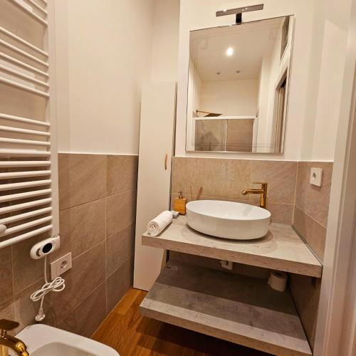 a bathroom with a sink and a mirror and a toilet at Cozy Apartment between Sempione, City Life and MiCo ! in Milan