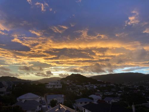 a sunset over a city with houses and mountains at Khandallah Harbour View BnB in Wellington