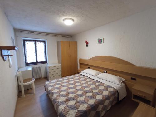 a bedroom with a bed and a desk and a window at LakyFamily in Cogolo