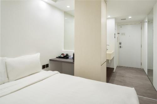 a white bedroom with a bed and a bathroom at Lion Peak Dickson in Singapore