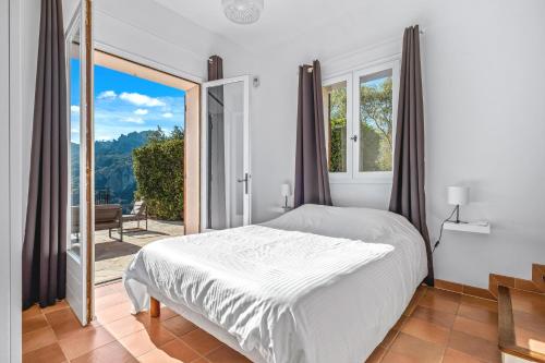ein weißes Schlafzimmer mit einem Bett und einem großen Fenster in der Unterkunft Villa Baladou in Fréjus