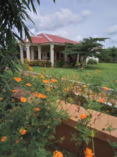una casa con un campo de flores delante de ella en Koh Ker Hotel and Restaurant, en Phumĭ Mréch