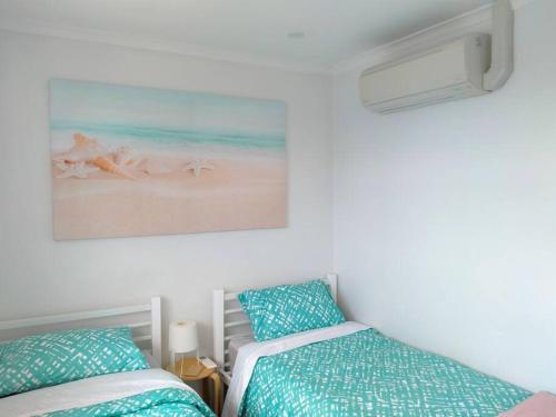 1 Schlafzimmer mit 2 Betten und einem Bild vom Strand in der Unterkunft Beachfront Tiny Townhouse Kurnell in Kurnell
