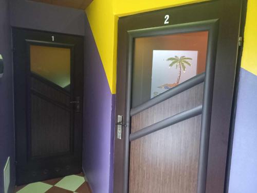a hallway with two doors and a palm tree painting at Miltex in Torzym