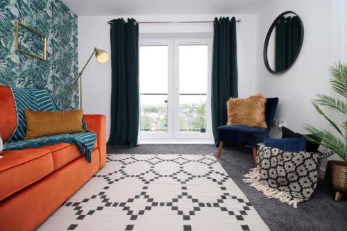 a living room with an orange couch and a window at Vibrant 2 Br Apartment close to Cardiff Central in Cardiff