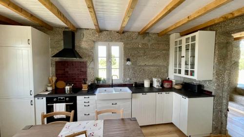 a kitchen with white cabinets and a wooden ceiling at Quinta da Cumieira Nova in Seia