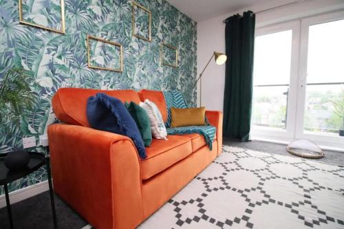 an orange couch in a living room with a wall at Vibrant 2 Br Apartment close to Cardiff Central in Cardiff