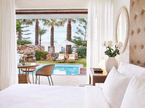 a bedroom with a bed and a swimming pool at Amirandes, A Grecotel Resort to Live in Gouves