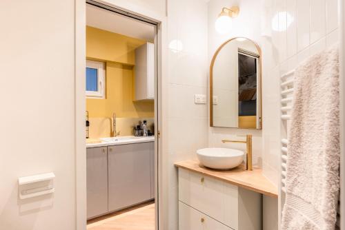 une salle de bain blanche avec un lavabo et un miroir dans l'établissement Charming flat - heart of Saint-Germain des prés, à Paris