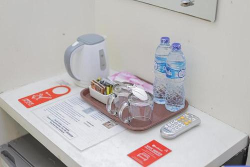 ein Tablett mit zwei Flaschen Wasser und einer Fernbedienung in der Unterkunft Kost K23 in Surabaya