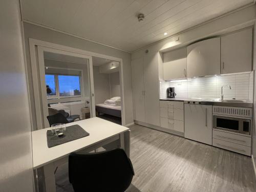 een witte keuken met een tafel en stoelen en een bed bij Vestfjordgata Apartment 17 in Svolvær