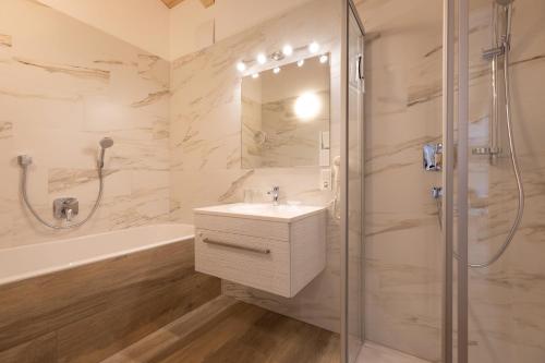 a bathroom with a sink and a shower and a tub at Alpenhof Chalets in Gerlos