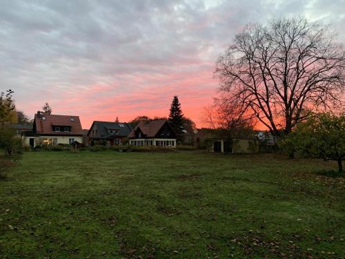 a house in a field with a sunset in the background at Ferienwohnung Himmelpfort in Himmelpfort