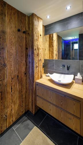 La salle de bains est pourvue de murs en bois et d'un lavabo blanc. dans l'établissement Chalet Aikoa, à Chamonix-Mont-Blanc