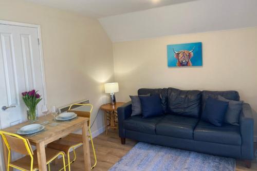 ein Wohnzimmer mit einem blauen Sofa und einem Tisch in der Unterkunft Burnbank Lodges in Spean Bridge