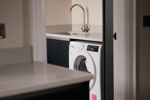 a kitchen with a washing machine and a sink at Three The Stables at Corrstown Village in Portrush