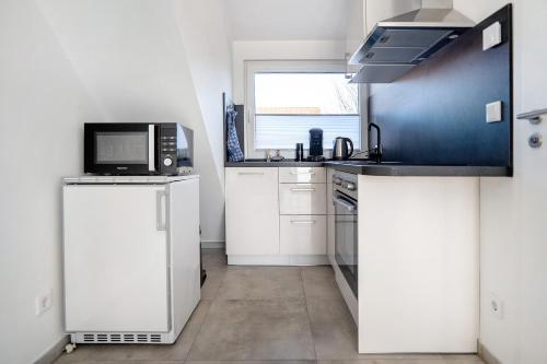 a kitchen with white cabinets and a microwave oven at Neubau Ferienwohnung mit Balkon in Gronau