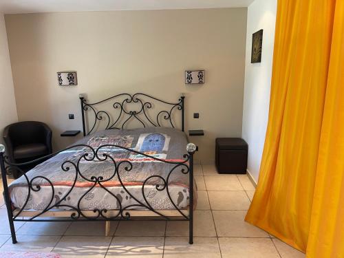 - une chambre avec un lit en fer forgé et un rideau jaune dans l'établissement Gite ALPILLES & piscine - Oliveraie Bio Mas de Cargane, à Entressen