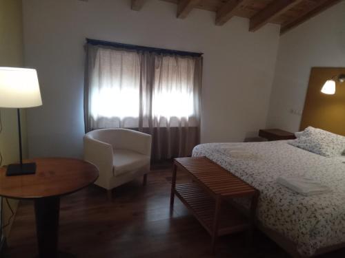 a bedroom with a bed and a chair and a window at Villabamba in Valdeavellano de Tera